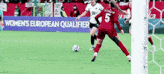 a woman is kicking a soccer ball in front of a sign that says ' women 's european qualifier '