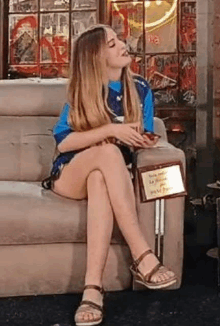 a woman is sitting on a couch with her legs crossed while holding a plaque .