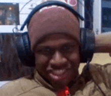 a man wearing headphones and a beanie is smiling and making a funny face .