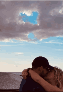 a man and woman kissing with a cloud in the sky