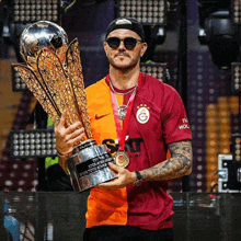 a man holding a trophy that says ' galatasaray ' on the front