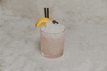 a glass of pink liquid with ice and a lemon slice