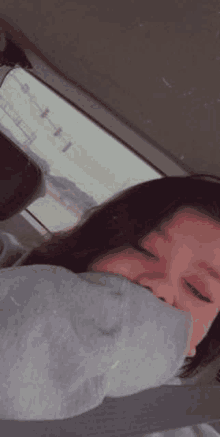 a woman is sleeping in the back seat of a car with her face covered .