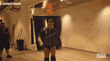 a man in a wrestling outfit is walking through a hallway with an exit sign