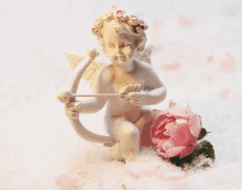 a statue of a cupid holding a bow and arrow next to a pink rose