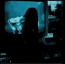 a woman with long black hair is standing in front of a television screen