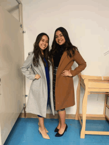 two women standing next to each other in a room with a sign that says emergency exit