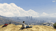 a man sits on top of a sandy hill with a helicopter in the background