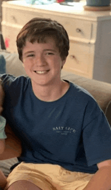 a young boy wearing a salt life t-shirt smiles for the camera