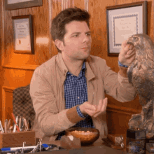 a man is sitting at a desk with a statue of an eagle and a certificate on the wall behind him