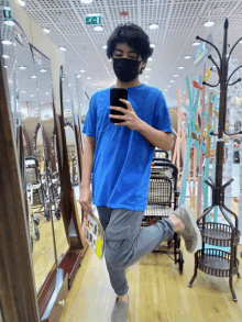 a man wearing a mask takes a selfie in front of a mirror in a store