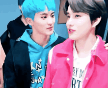 a boy with blue hair is standing next to another boy in a pink jacket