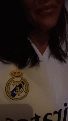 a woman is wearing a white shirt with the real madrid logo on it