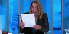 a woman is holding a piece of paper in front of her face .