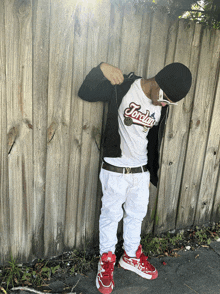 a man wearing a jordan shirt is leaning against a wooden wall