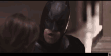 a close up of a man in a batman costume with the letter l on the bottom