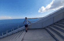 a man stands on a set of stairs looking out over the ocean