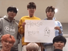 a group of young men are standing next to each other and holding a sign that says `` please leave '' .