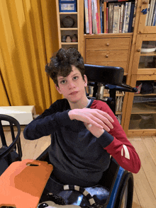 a young boy in a wheelchair with his hands folded