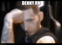 a blurry picture of a man with his hand on his head and the words `` denny rn '' above him .