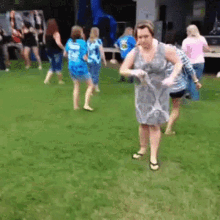 a group of women are dancing in a grassy field and one of them is wearing a shirt that says ' a '