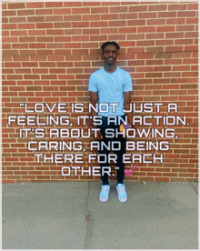 a man is standing in front of a brick wall with a quote that says love is not just a feeling it 's an action