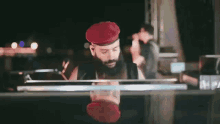 a man with a beard wearing a red hat is standing in front of a glass door