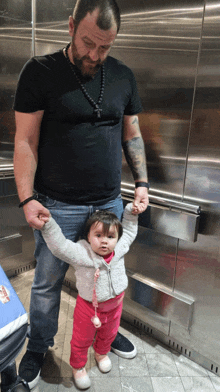 a man is holding a little girl 's hand in front of a refrigerator