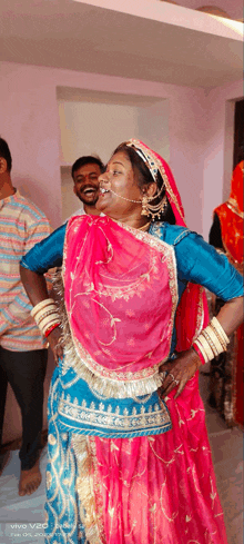 a woman in a pink and blue dress is dancing in front of a vivo v20 camera