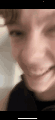 a close up of a person 's face with a blurry background and a smile on their face .