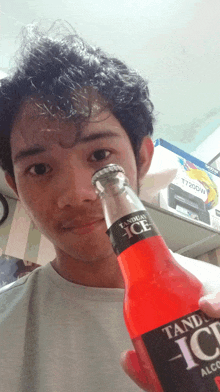 a young man is holding a bottle of tangy ice alcohol