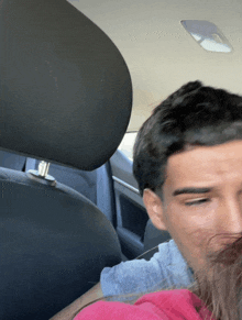 a man sitting in the back seat of a car looking at the camera