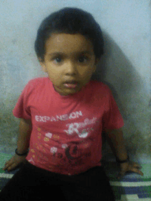 a little boy wearing a red expansion shirt