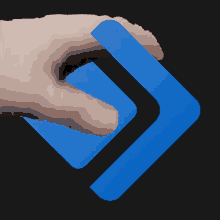 a hand is touching a blue arrow on a dark background