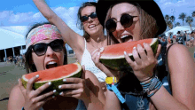 three women are eating watermelon at a festival and one has a wristband with a tag that says ' a ' on it