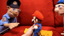 a police officer talking to a mario puppet on a red couch