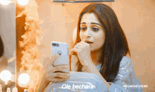 a woman sitting in front of a mirror looking at her phone with the words " ole bechara " on the bottom