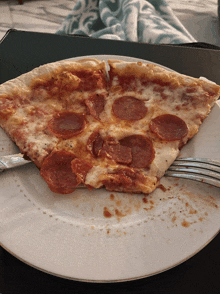 a white plate topped with a slice of pepperoni pizza and a fork