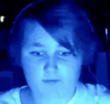 a close up of a person 's face in a dark room with a blue light behind them .