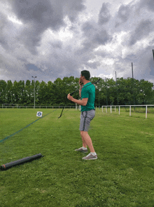 a man in a green shirt is holding a bow in a field