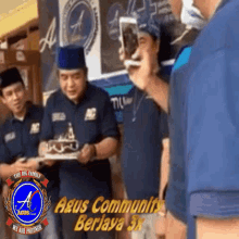 a group of men are standing around a cake with the words " the big family " written on the bottom