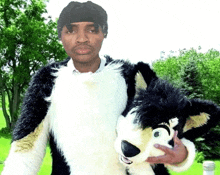 a man in a fursuit holds a black and white stuffed animal