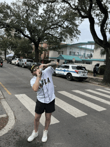 a man in a la shirt stands in front of a police vehicle