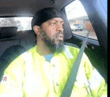 a man with a beard is sitting in the back seat of a car wearing a seat belt .