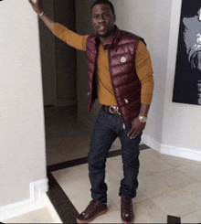 a man wearing a maroon vest and a yellow shirt stands in a hallway