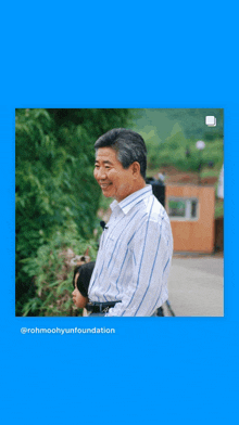 a man in a striped shirt is smiling in front of a blue background