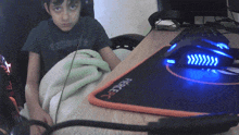 a boy in a vancouver shirt sits at a desk next to a fierce pc mouse pad