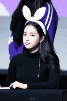 a woman wearing a headband with bunny ears is sitting at a table