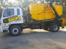 a dump truck with a yellow dumpster attached to it is parked on the side of the road .