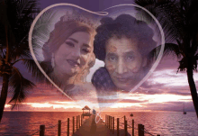 a couple standing on a dock with a heart shaped frame around them